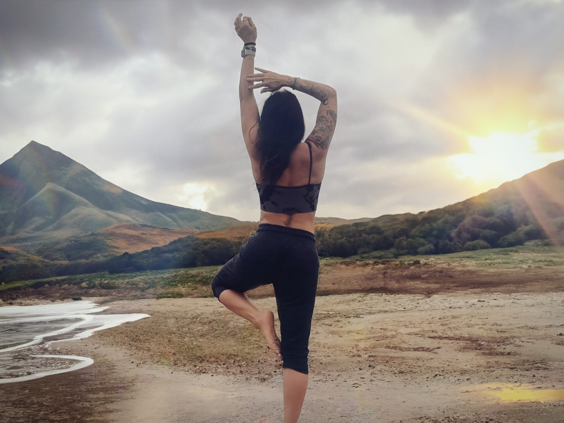 Woman standing in a mountain landscape with her arms raised